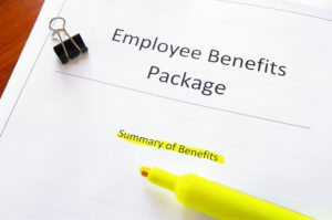 An employee benefits program document with "Summary of Benefits" highlighted in yellow and a binder clip nearby.
