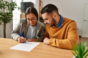 Happy, smiling couple signing small business contracts.