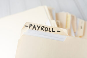 A close-up of a folder labeled 'PAYROLL', with other file tabs in the background.