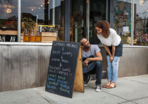 Chalkboard sign outside a small business advertising fresh goat's milk cheeses, showcasing effective small business advertising tips with a welcoming storefront.