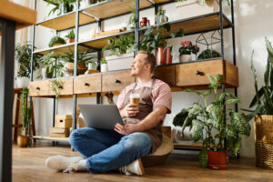 Person sitting cross-legged with a laptop and coffee cup, surrounded by plants and a shelving unit, symbolizing a relaxed and productive workspace for small business owners exploring MarTech for small businesses.