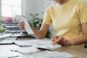 A person in a yellow shirt holding a receipt and using a calculator, focusing on expense tracking for small businesses.
