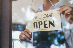 Wooden 'We Are Open' sign held by a hand, symbolizing small business readiness and growth, related to the One Big Beautiful Bill Act small business benefits.