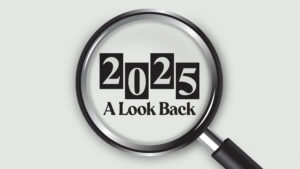 Hero image featuring a magnifying glass centered on the year '2025' in bold, white numbers against black squares, with the phrase 'A Look Back' below. The magnifying glass rests on a light gray background, symbolizing reflection and analysis of the 2025 year in review and the top stories for small business owners on Small Business Xchange.