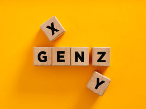 Generational marketing concept image with wooden letter blocks spelling Gen X, Gen Y, and Gen Z on a bright yellow background.